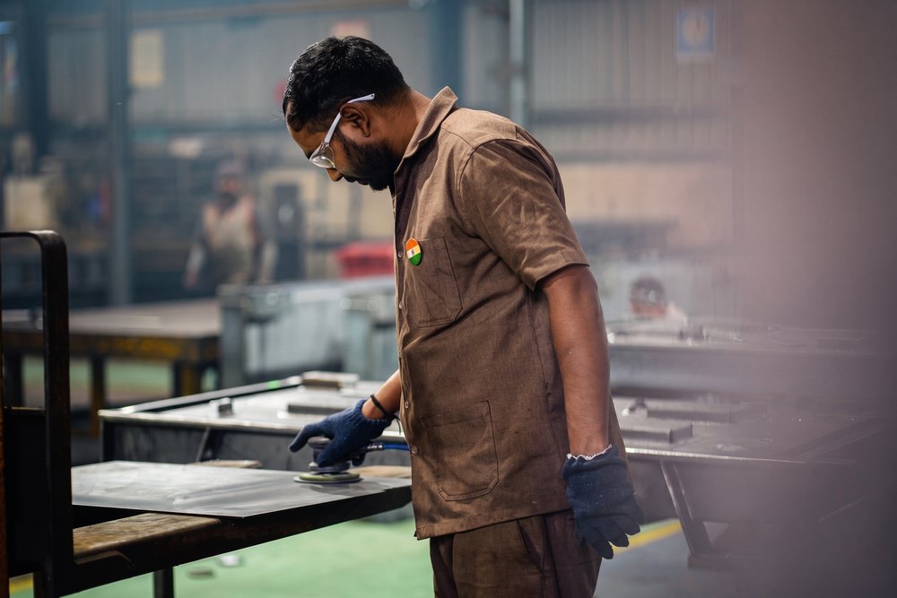 A fabricator finishing a formed sheet-metal component at the bench